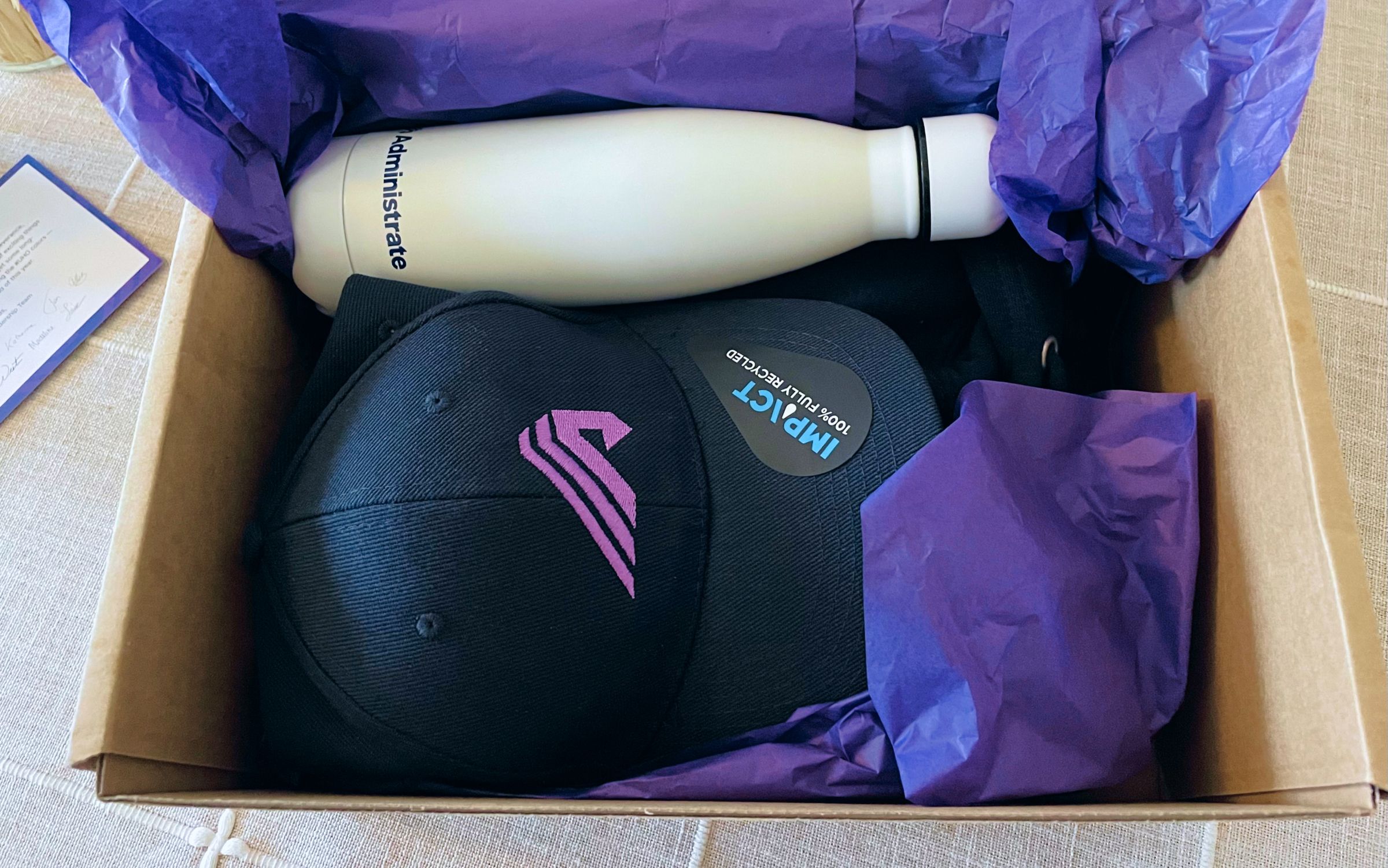 Photo of a box with an Administrate-branded cap, water bottle, and hoodie