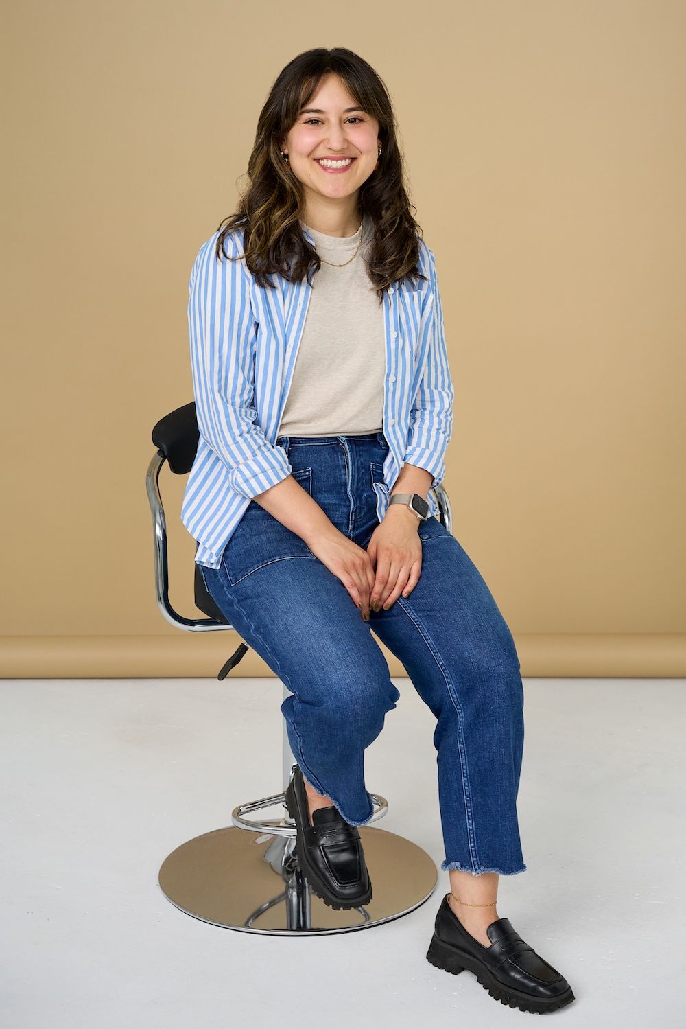 Alex Lash sitting on a chair in a shirt and jeans.